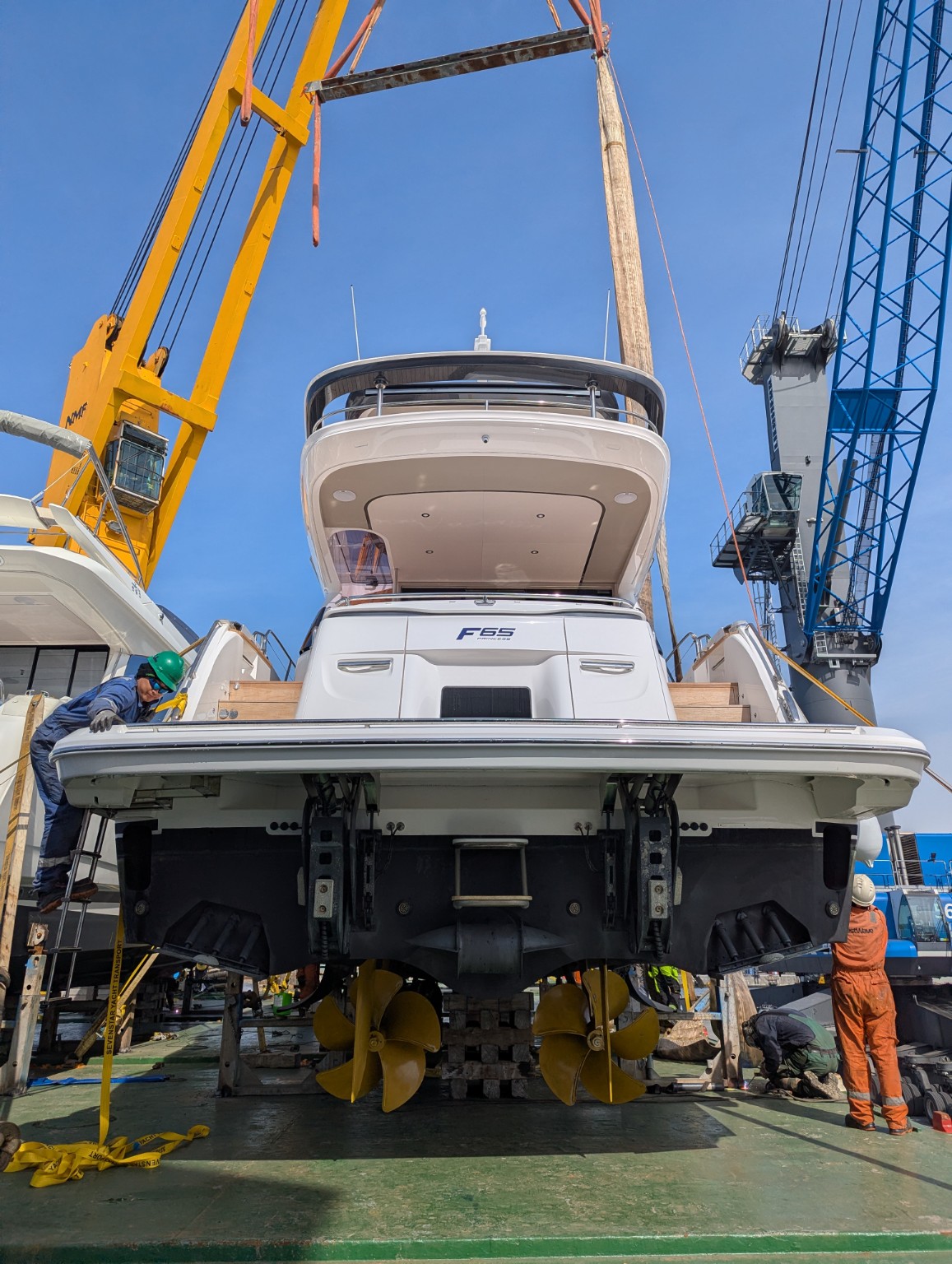 Stern and underwater gear of a Princess F65 motor yacht set down on cradles on a cargo vessel deck